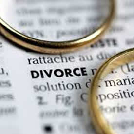 Two wedding rings laying on top of a dictionary page for Divorce to represents the loss and mourning a grief that a counselor and therapy can help with.