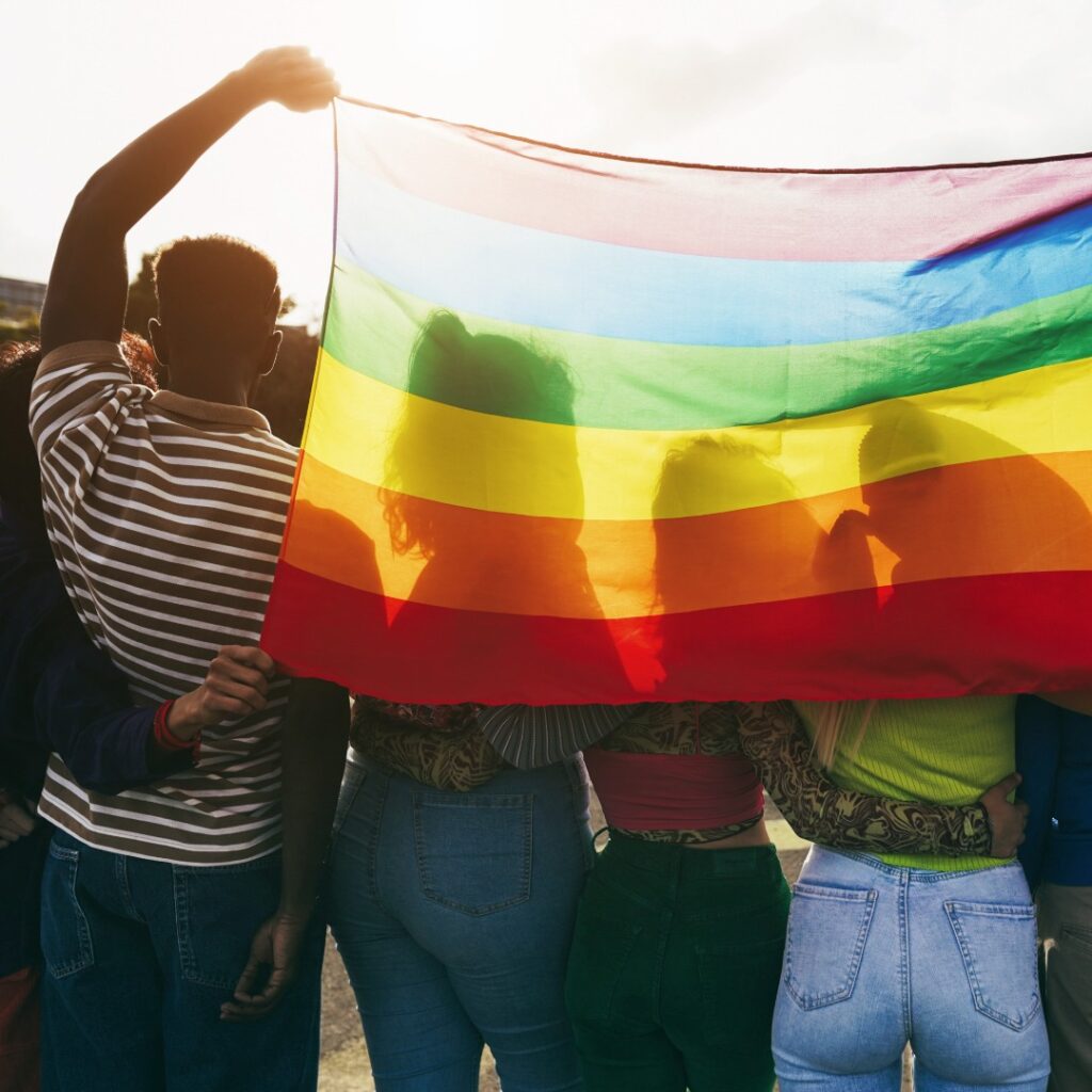 group of people holding up a LGBT rainbow flag to show counselor as a LGBTQ+ Ally