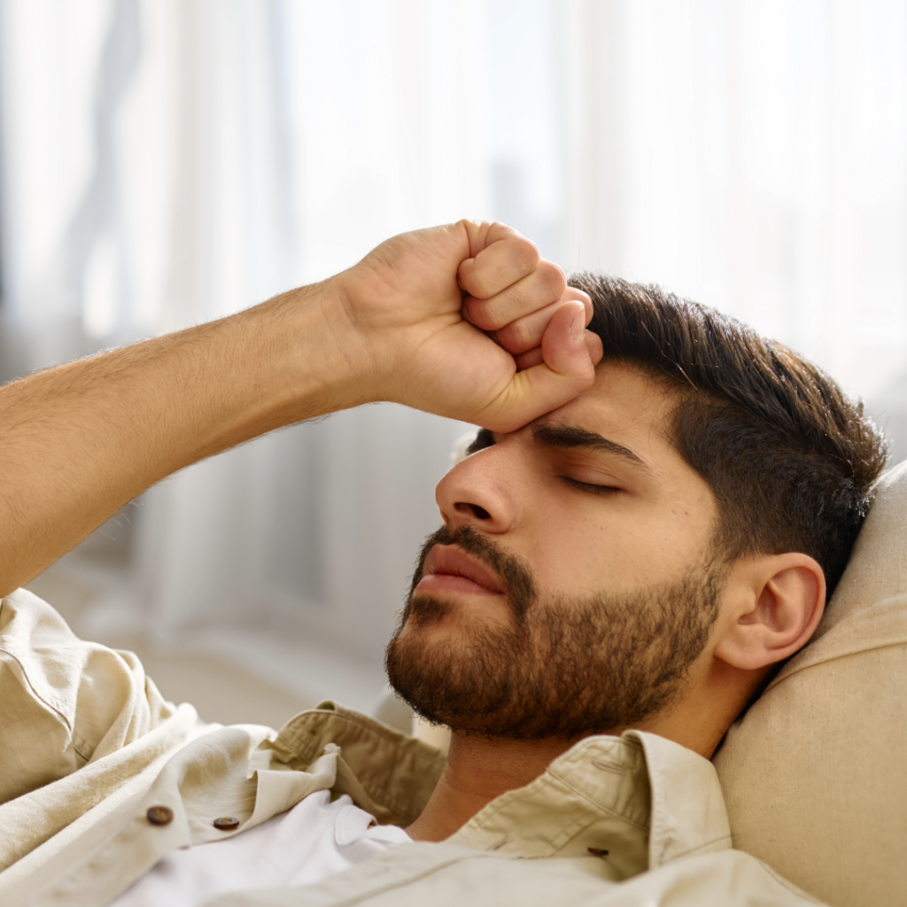 A man leaning back in a counseling chair, hand against his forehead in frustration.