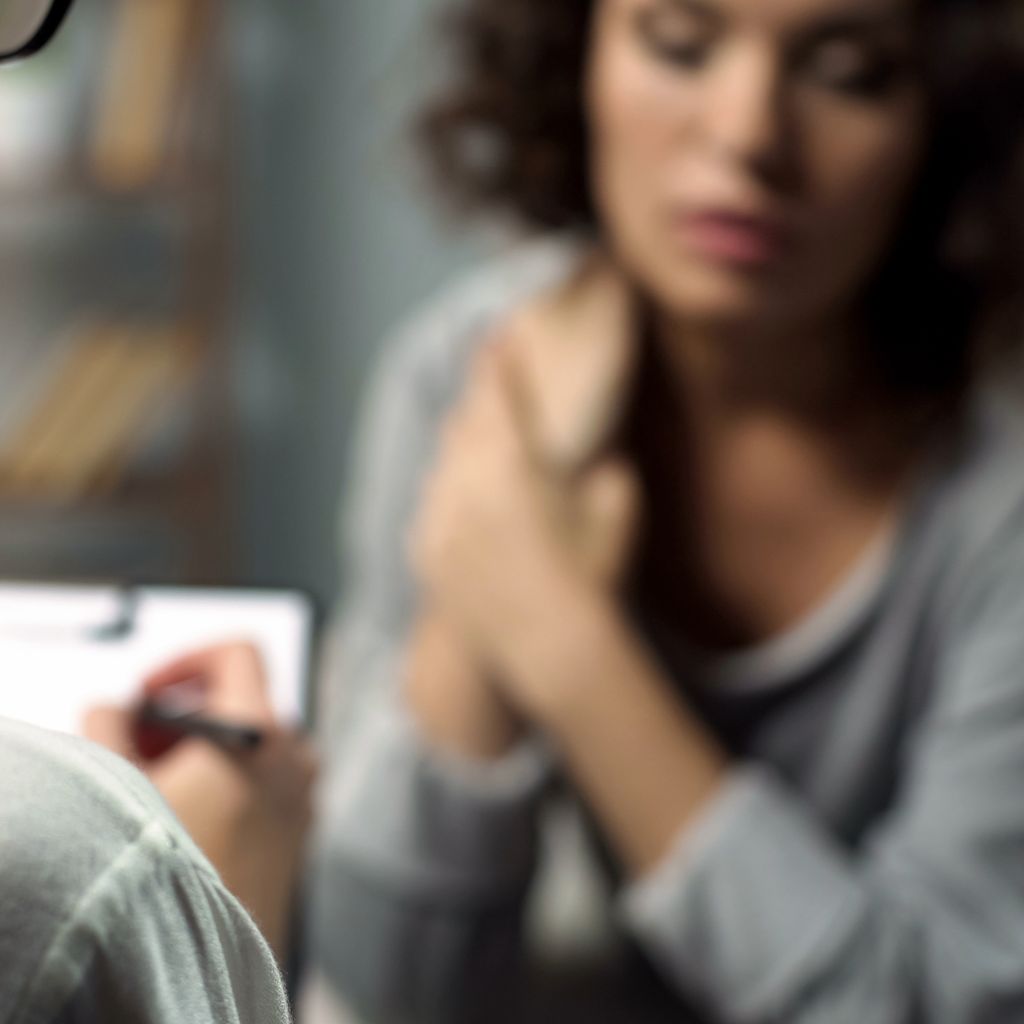 view looking over should of counselor writing notes with a depressed woman in therapy