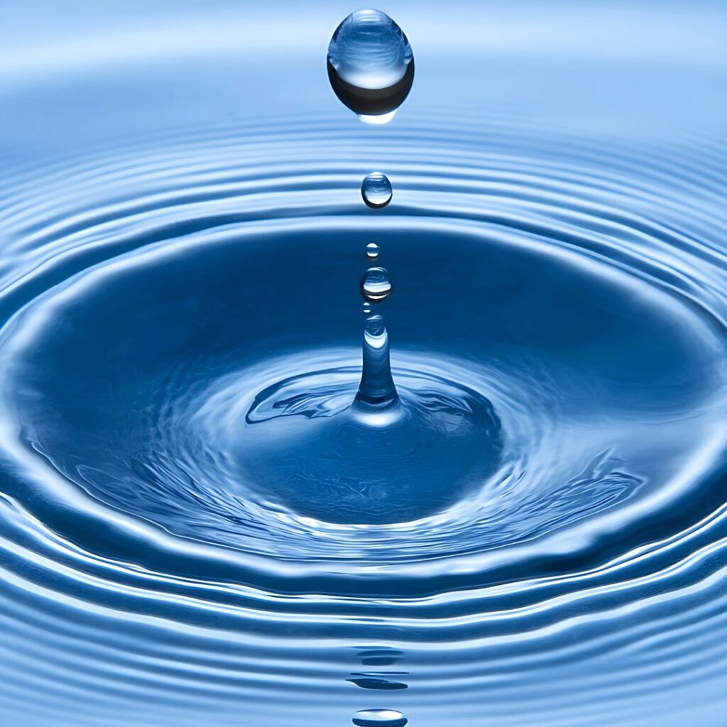 drop of water falling in water, creating ripples